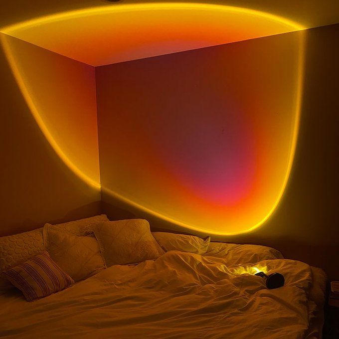 a bed with white sheets and pillows in a room that has an orange light on the wall