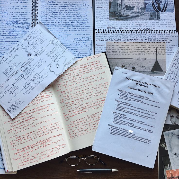 an open book sitting on top of a wooden table next to eyeglasses and papers