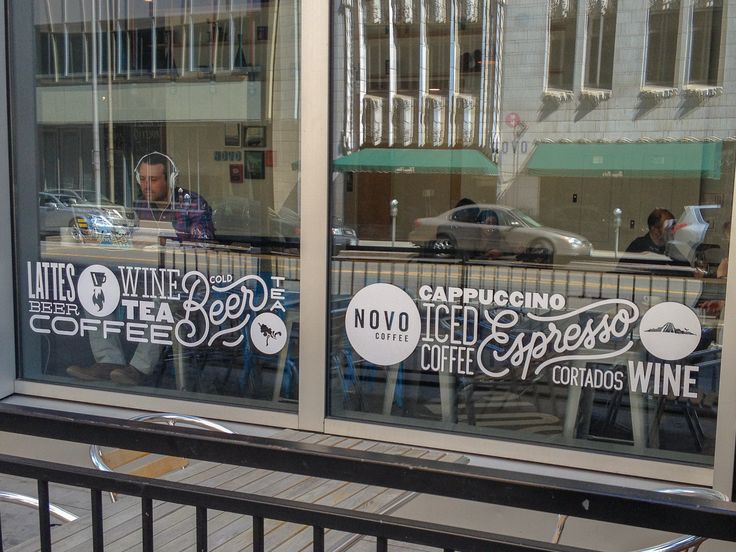 the reflection of a man sitting at a table in a coffee shop window