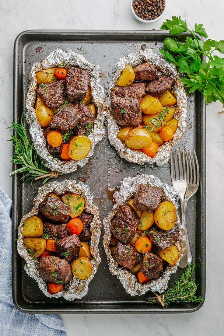 four pies with meat, potatoes and carrots on a baking sheet next to a fork