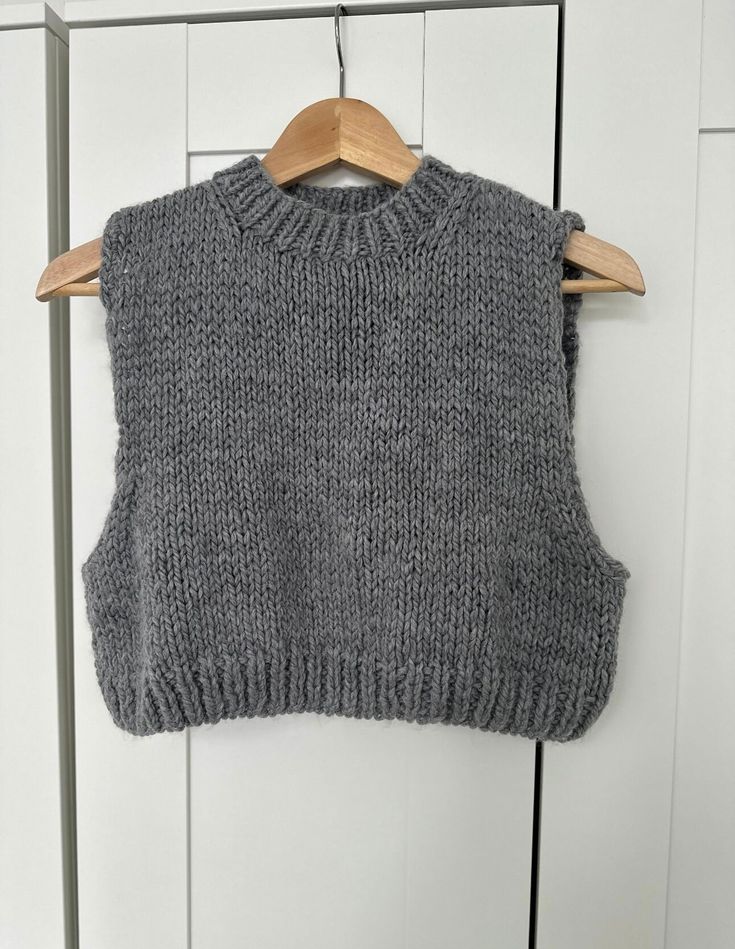 a gray sweater hanging on a wooden hanger