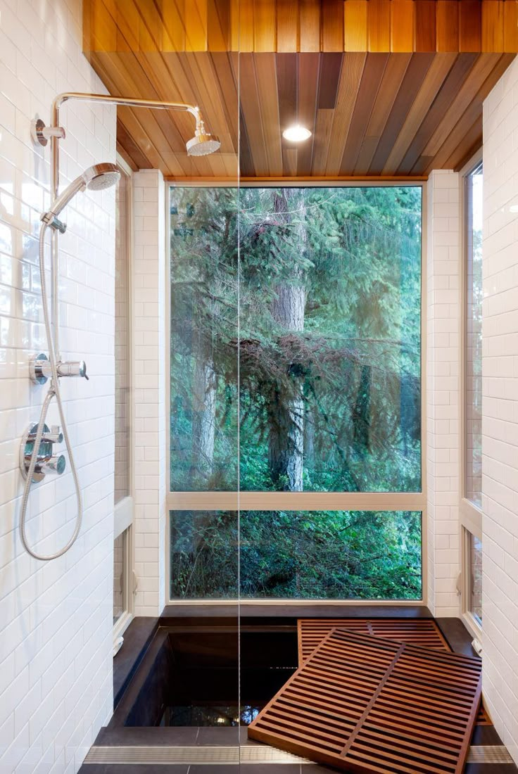 a bathroom with a large window and wooden shower head in the corner, along with a walk in shower