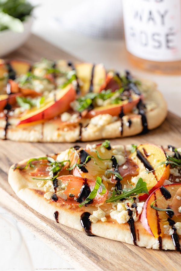 two pizzas sitting on top of a wooden cutting board