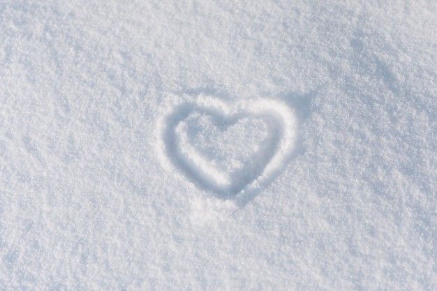 a heart drawn in the snow on a sunny day