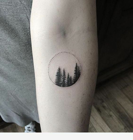 a person with a tattoo on their arm that has pine trees in the circle and dots