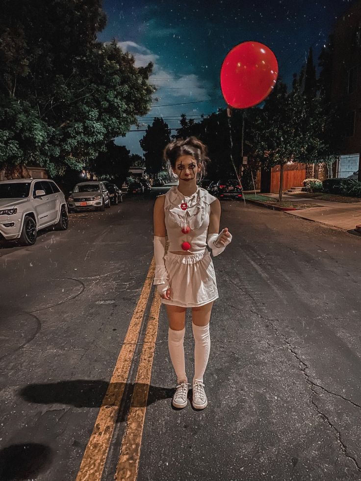 a woman standing in the middle of a street with a red balloon above her head