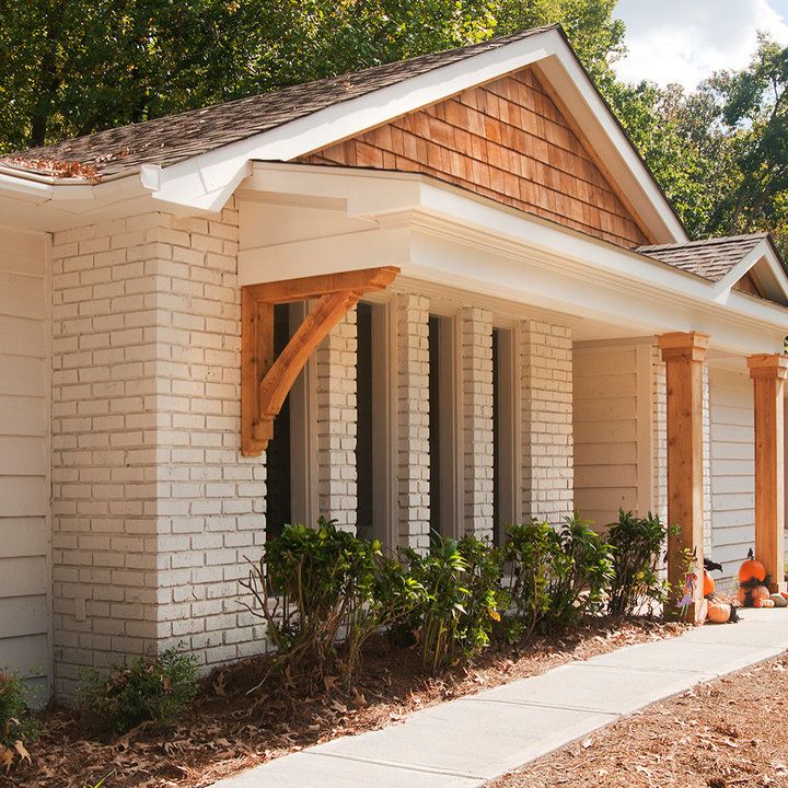 a white brick house with wood trim on the roof