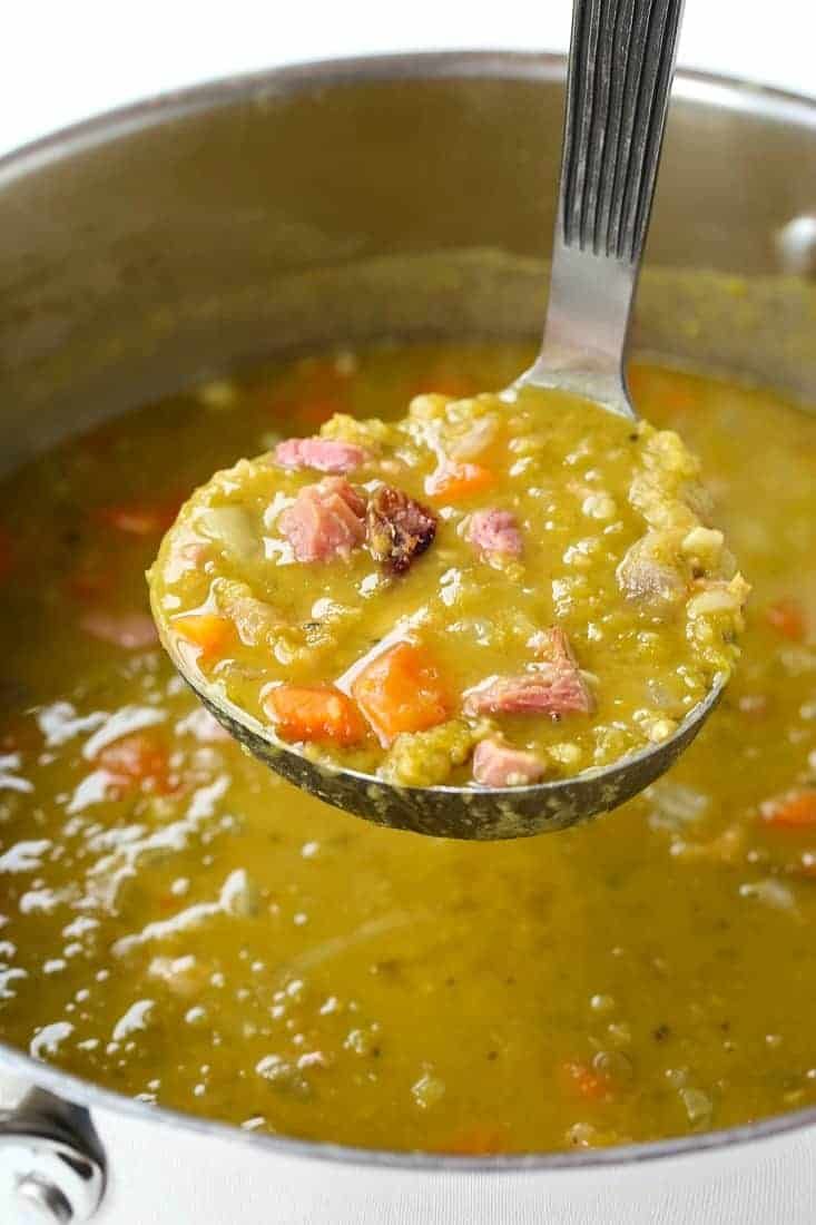 a ladle full of soup is being held by a spoon with meat and vegetables in it