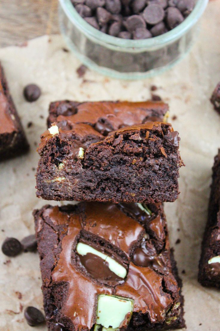 chocolate brownies with white and green frosting on top, next to a bowl of chocolate chips