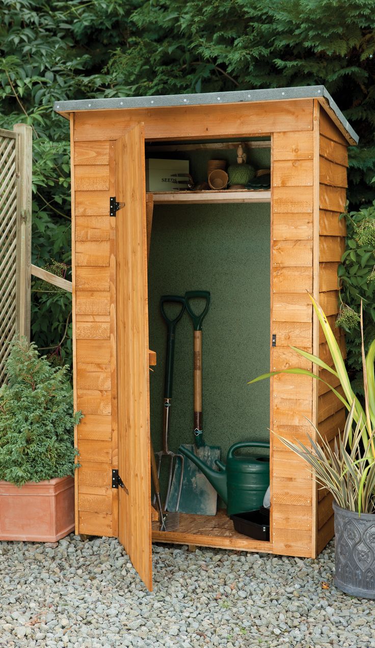 a garden shed with its door open and gardening tools in the storage area next to it