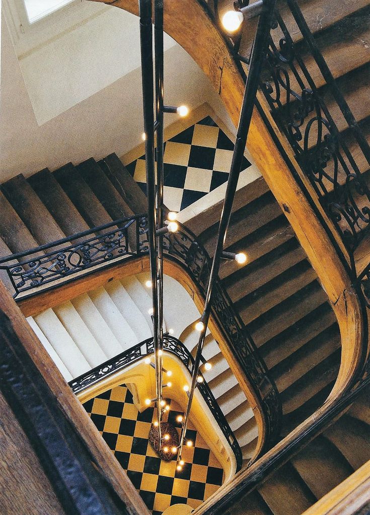 an overhead view of a spiral staircase with checkered flooring and chandeliers