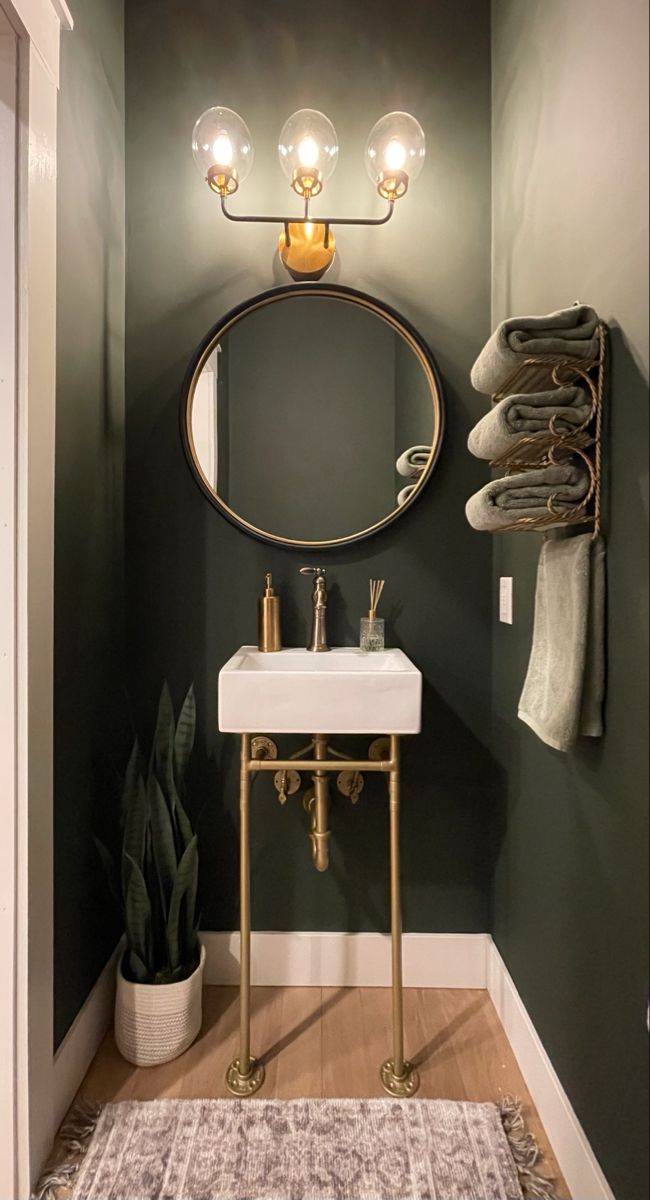 a bathroom with green walls and a round mirror on the wall above a white sink