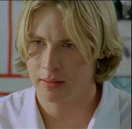 a man with blonde hair wearing a white shirt