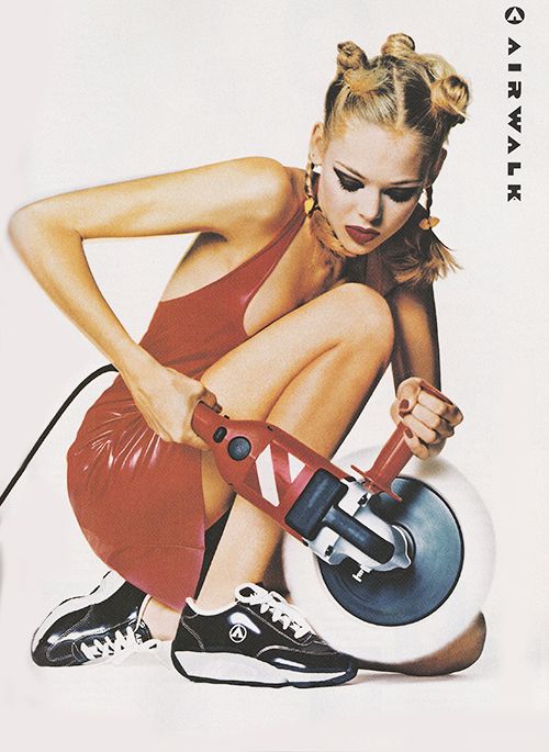 a woman sitting on top of a ball with a machine in her hand and wearing sneakers