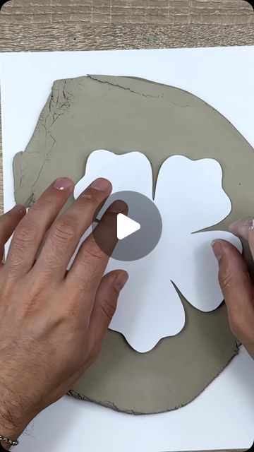 two hands are working on a paper flower