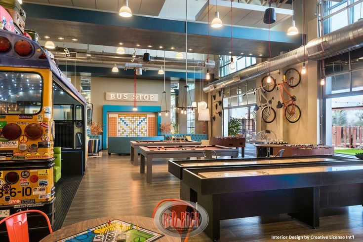 an indoor recreation room with ping pong tables and bikes on the wall behind it