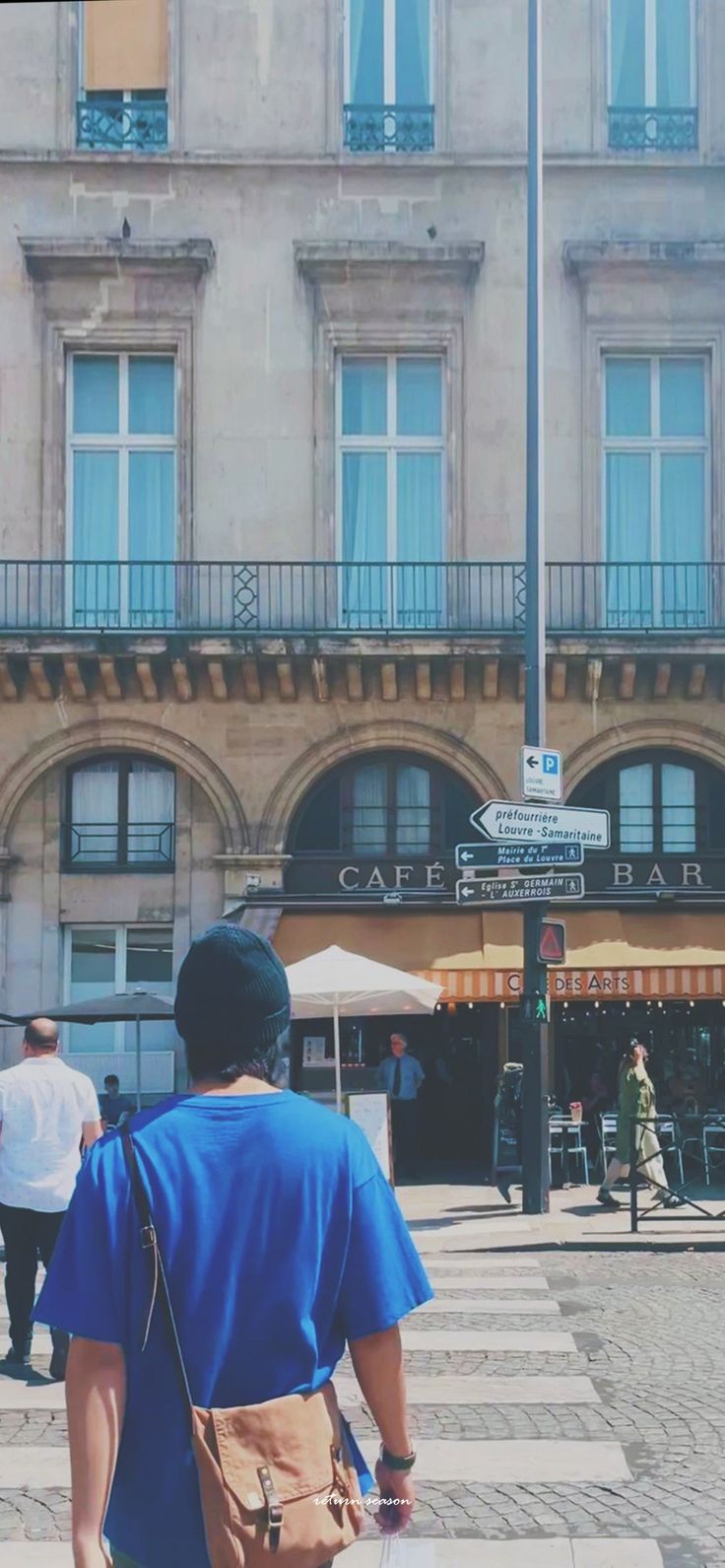 a man walking across a cross walk in front of a building