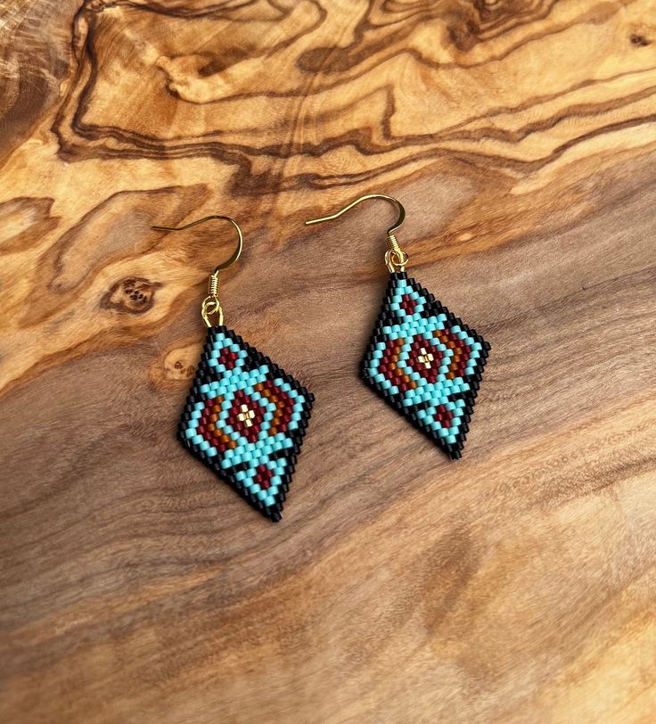 a pair of beaded earrings sitting on top of a wooden table