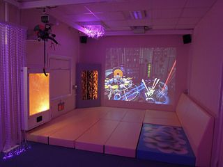 an empty room with purple lighting on the walls and a projection screen in the corner