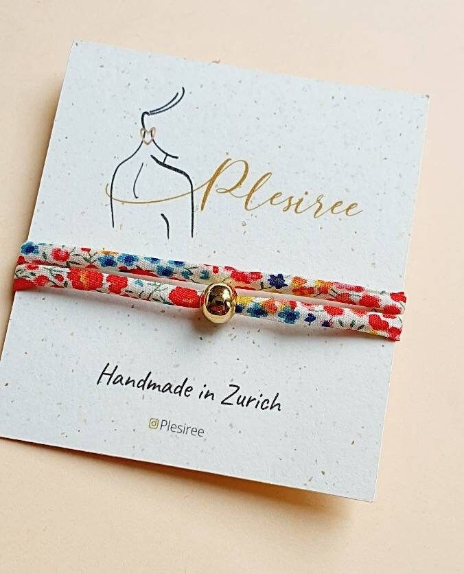 two bracelets with flowers on them sitting on top of a card