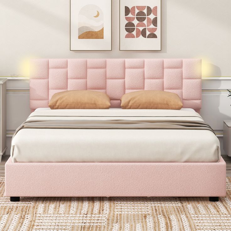 a bed with pink headboard and pillows in a white room next to two pictures on the wall