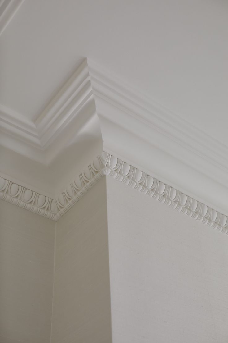 the corner of a room with white walls and ceiling molding on it's sides