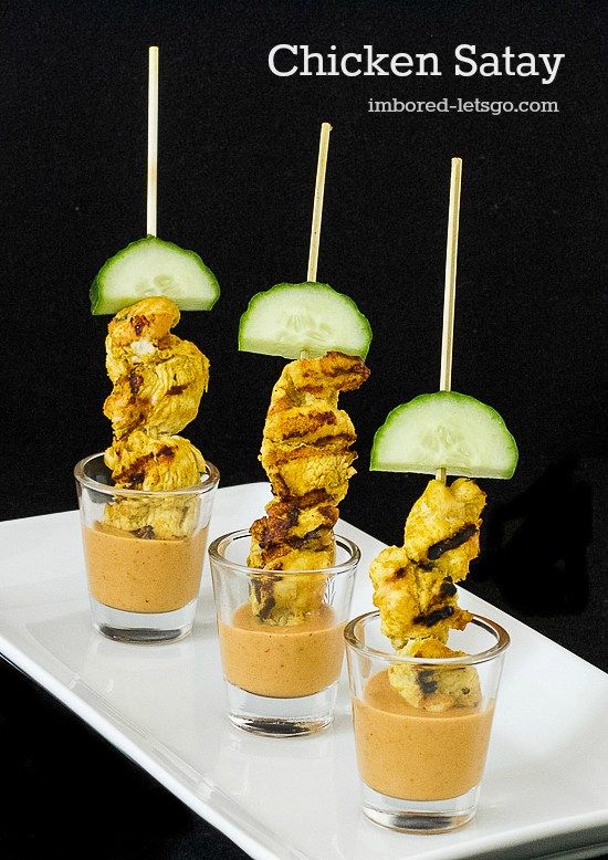 chicken satay on skewers with cucumbers and peanut butter in small glasses