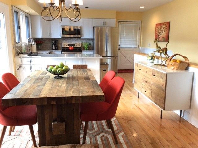 a kitchen table with red chairs and a bowl of fruit on top of it in front of an open floor plan