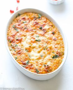 a casserole dish with cheese and vegetables in it on a white counter top