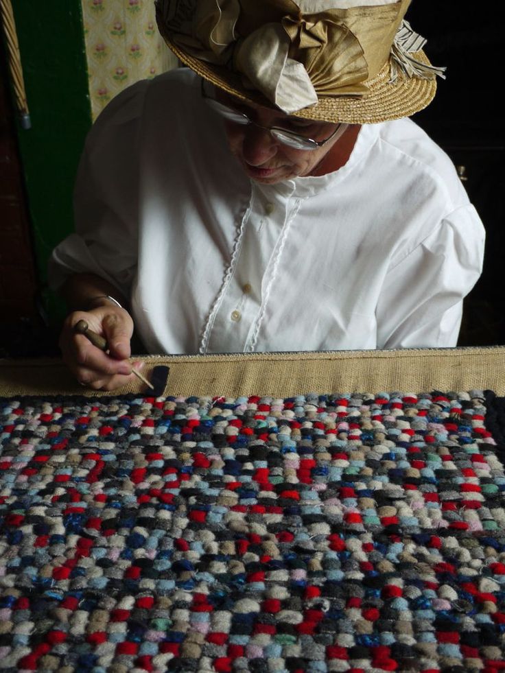 a man in white shirt and straw hat working on a piece of cloth with scissors