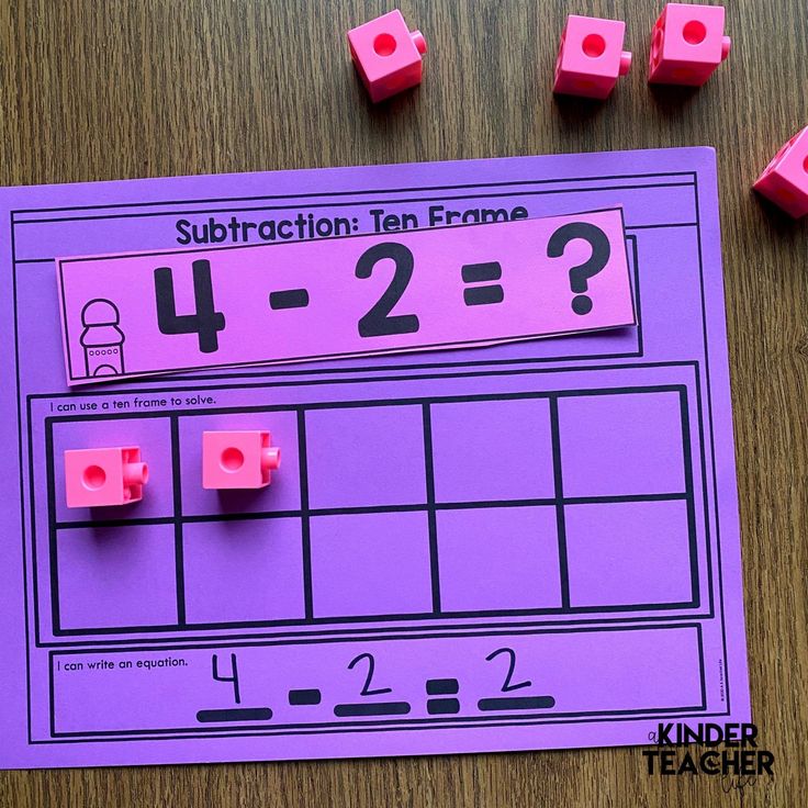 a purple piece of paper next to some pink cubes on top of a wooden table