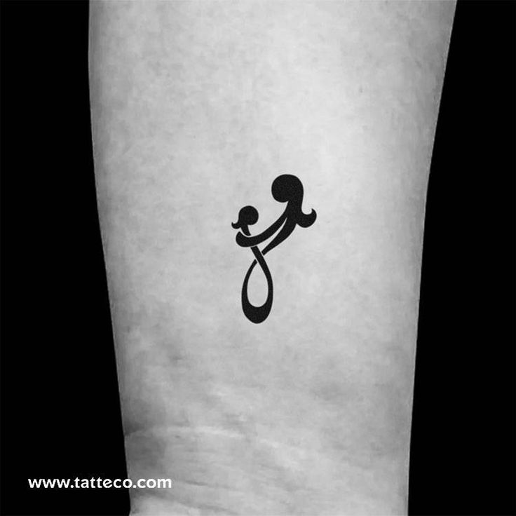 a small tattoo on the leg of a person holding a baby in her arms,