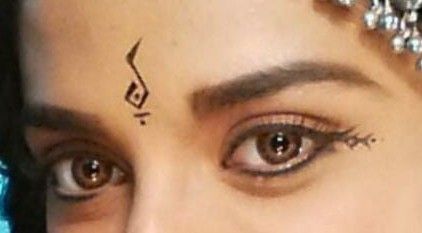 a close up of a woman's face with tattoos on her forehead and eyebrows