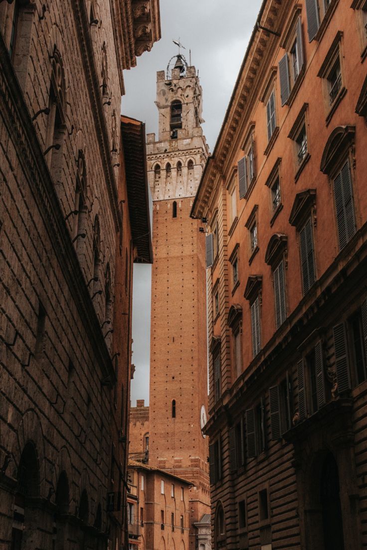 an alley way with tall buildings and a clock tower in the background