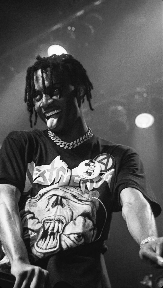 a man with dreadlocks on his head standing in front of a microphone and wearing a t - shirt