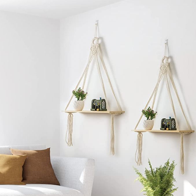 two hanging shelves with plants on them next to a white couch in a living room