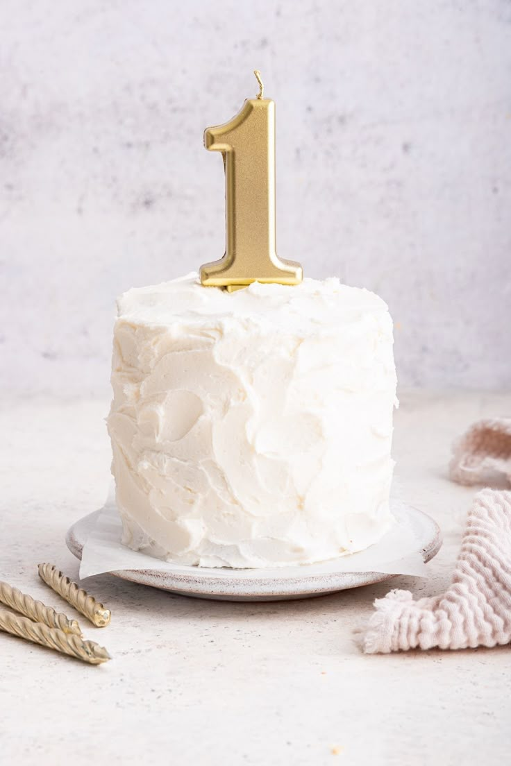 a white frosted cake with a gold one on top