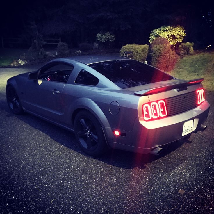 a car that is sitting in the street with its tail lights turned on at night