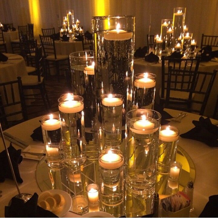 candles are lit on the table with clear glasses and silverware in front of them