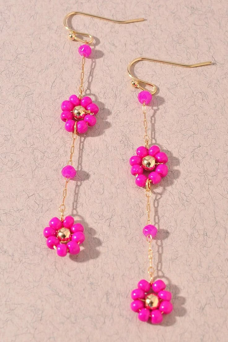 pink flowers are hanging from gold chain earrings