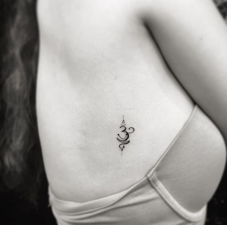 black and white photo of woman's chest with an omastha tattoo on it