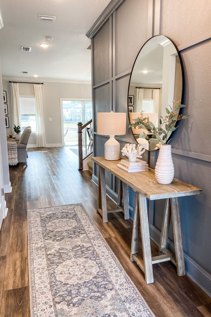 a living room with a large mirror on the wall next to a wooden table and rug