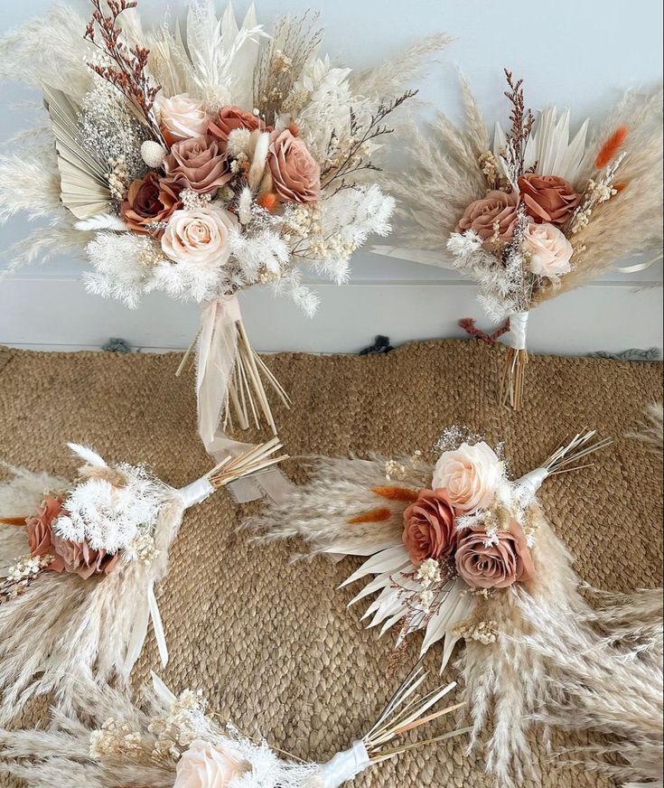 three bouquets with flowers and feathers on a burlocked tablecloth background