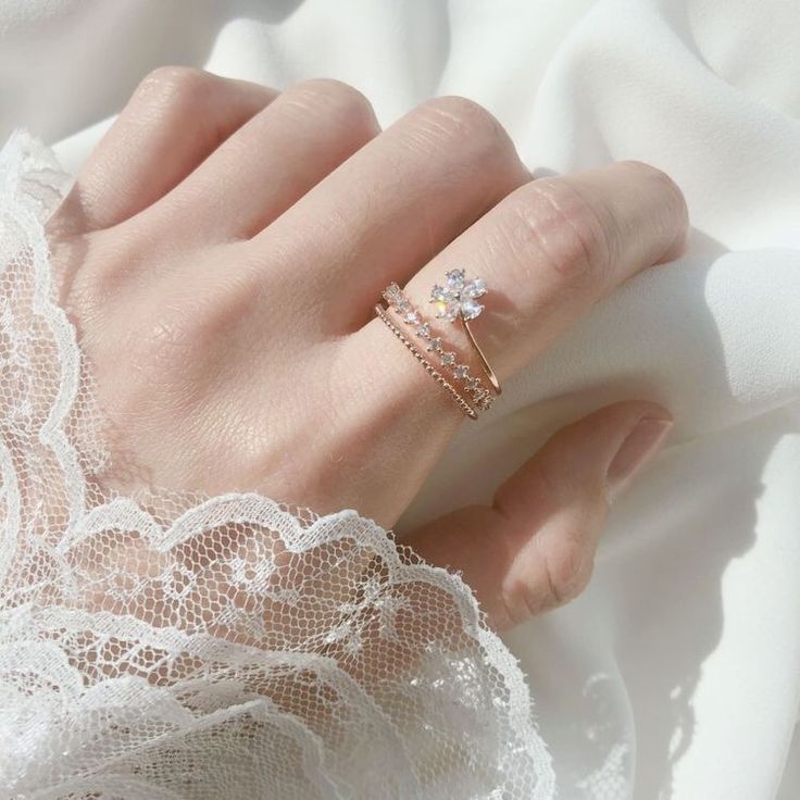 a woman's hand with two rings on top of her finger and white lace