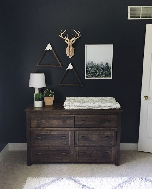 a baby crib in the corner of a room with two deer head mounted on the wall