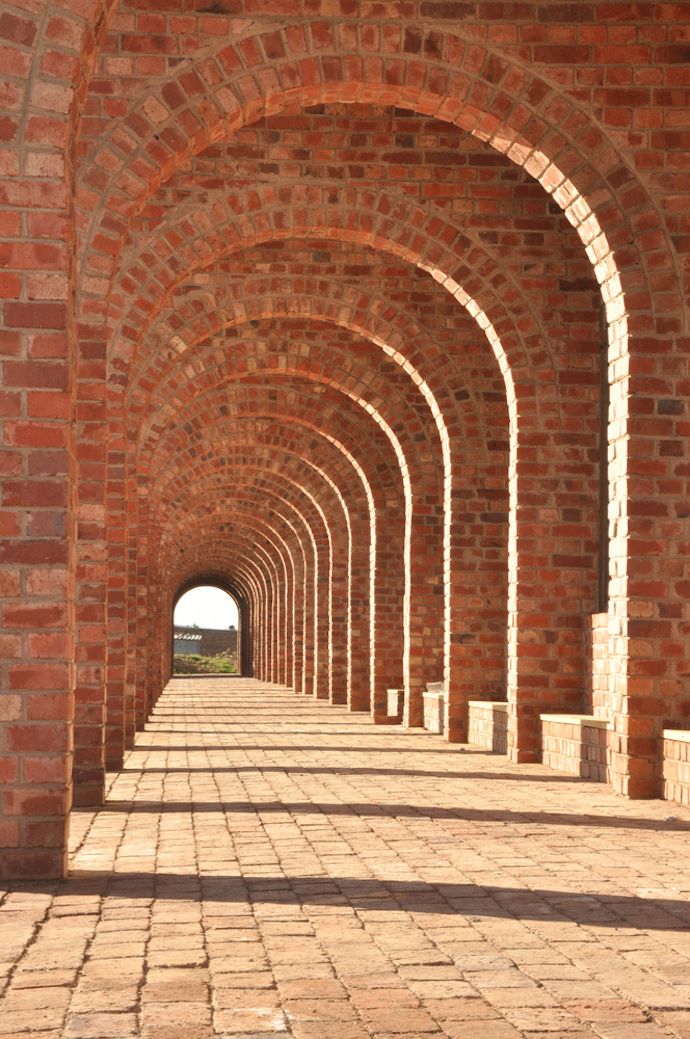 an arched brick walkway with benches on either side