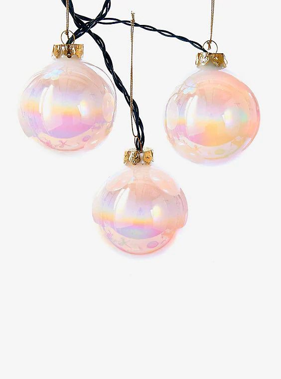 three pink glass ornaments hanging from a black cord on a white background with no one around them