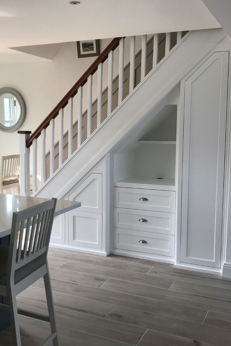 a room with white walls and wooden flooring under a stair case in an attic