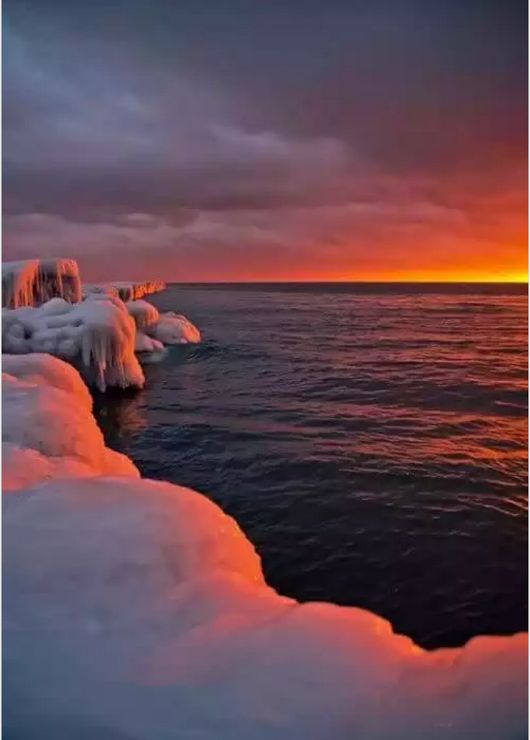 the sun is setting over some ice covered water