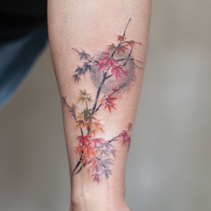 a woman's leg with a tattoo on it that has flowers and leaves growing out of it